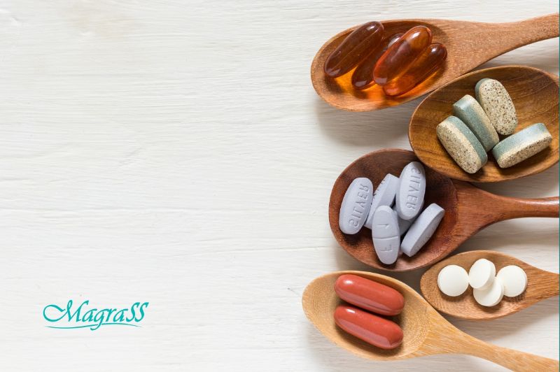 Assortimento de frutas e vegetais frescos com amêndoas e suplementos vitamínicos em uma mesa de madeira.